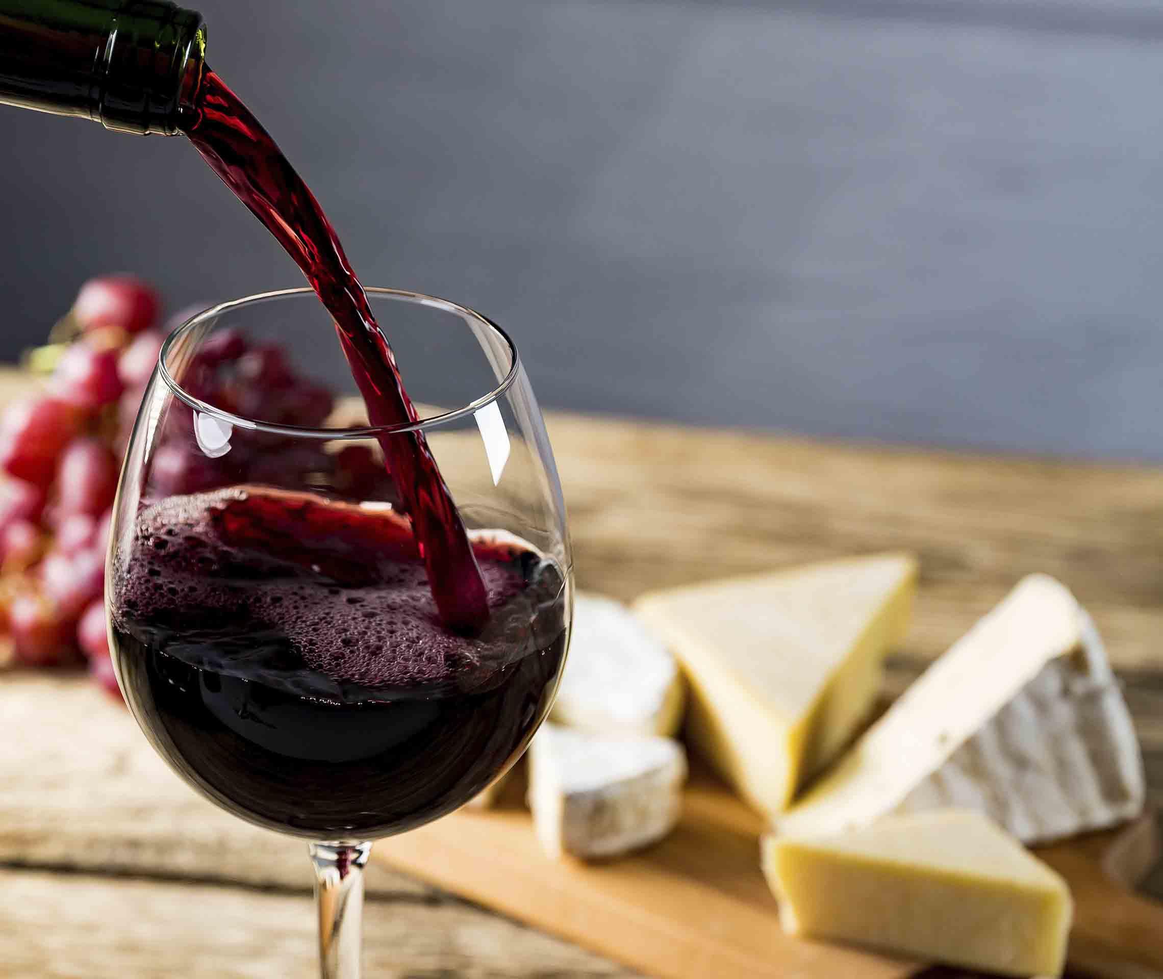 Migräne-Auslöser Alkohol: Jemand schenkt sich ein Glas Rotwein ein.