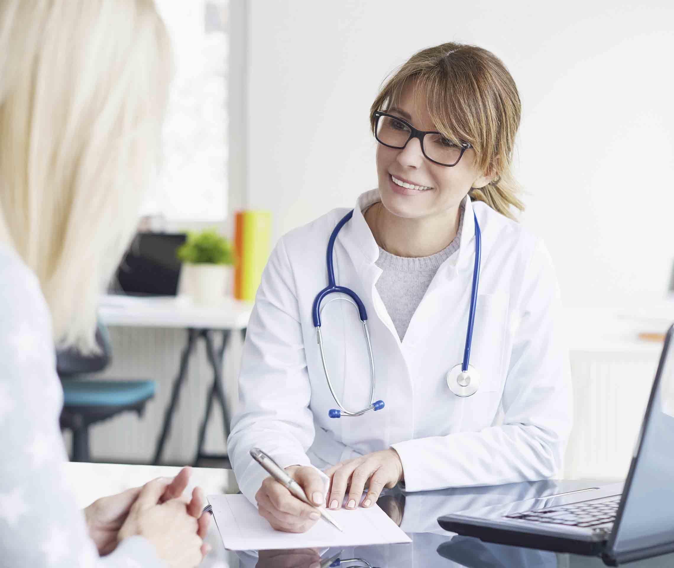 Eine Ärztin macht sich Notizen, während ihre Patientin erklärt, wo, wie, wann und wie lange sie bereits unter Migräneanfällen leidet.