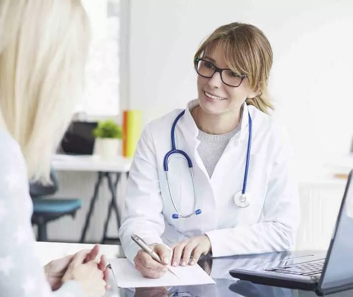 Eine Ärztin macht sich Notizen, während ihre Patientin erklärt, wo, wie, wann und wie lange sie bereits unter Migräneanfällen leidet.