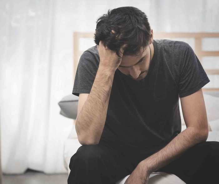 Junger Mann ist erschöpft, weil sich eine Migräneattacke anbahnt.