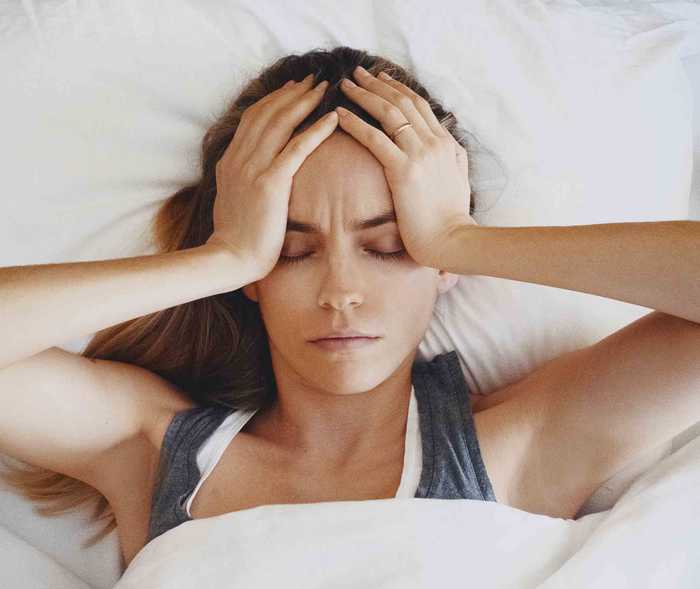 Frau hält sich wegen Migräne-Symptomen den Kopf.