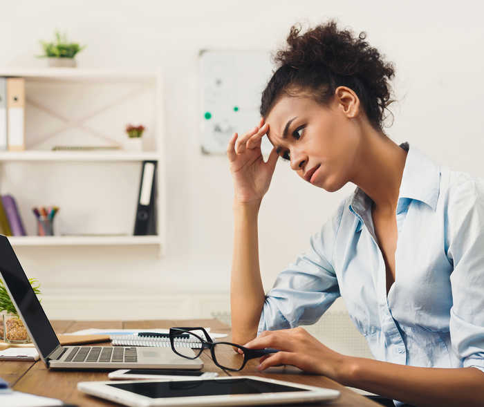 : Frau vor Laptop hält sich die Hand an den Kopf, sie möchte den Migräne-Schnelltest durchführen.