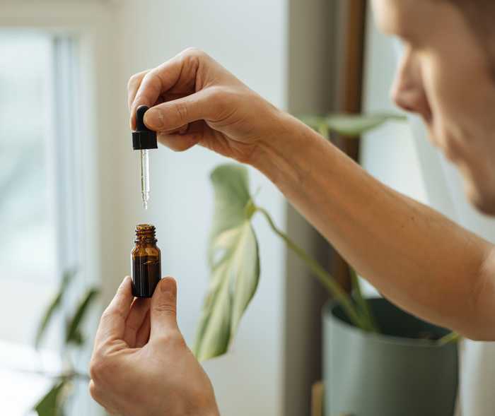 Ein Mann entnimmt einer kleinen Medizinflasche mit einer Pipette einige Tropfen Flüssigkeit.