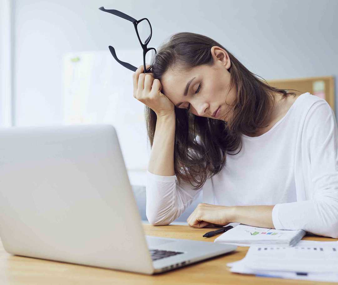 Müde Frau am PC hat Migräne durch Schlafmangel.