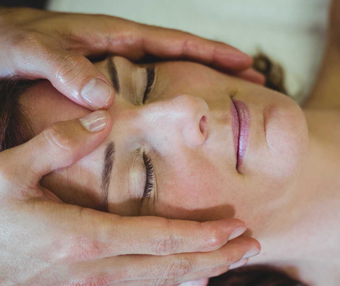 Eine Patientin versucht, sich während der Massage  zu entspannen und Migräne oder Kopfschmerzen kurz zu vergessen.