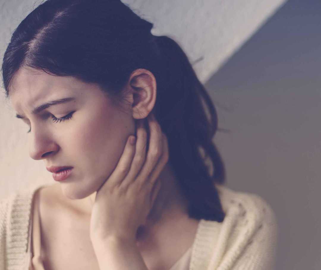 Frau hat Spannungskopfschmerz, der durch eine Nackenverspannung verursacht wurde.