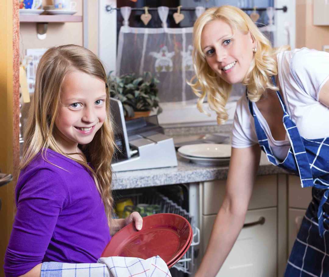 Migräne und Familie: Frau und Kind räumen gemeinsam den Geschirrspüler aus.