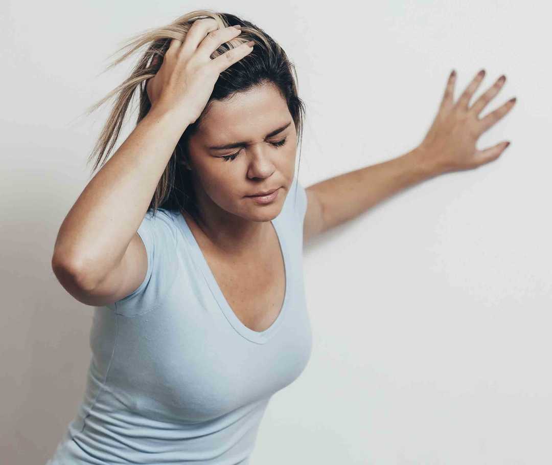 Frau leidet unter Schwindel, einem Symptom für einen migränösen Infarkt.