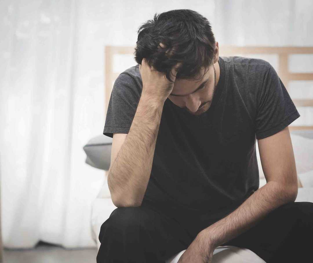 Junger Mann ist erschöpft, weil sich eine Migräneattacke anbahnt.