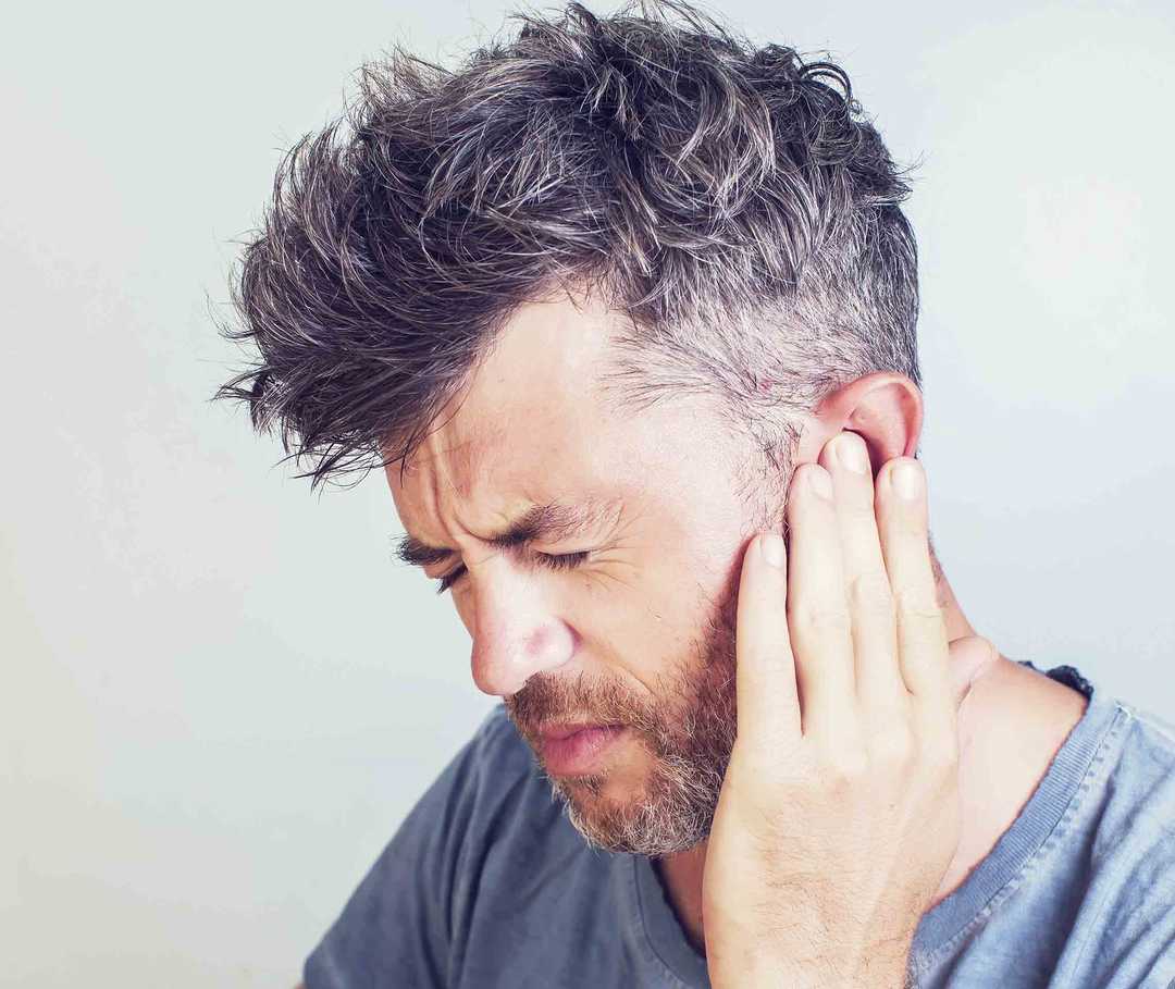 Mann hält sich das schmerzende Ohr. Tinnitus kann durch eine Basilarismigräne ausgelöst werden. Mann hält sich das schmerzende Ohr. Tinnitus kann durch eine Basilarismigräne ausgelöst werden.