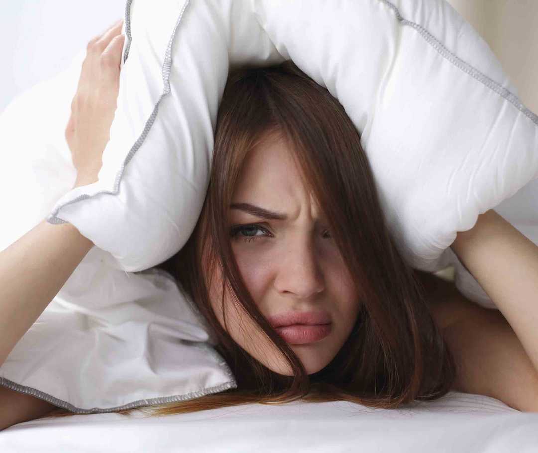 An Migräne ohne Aura leidende Frau hat eine Migräneattacke und liegt im Bett.