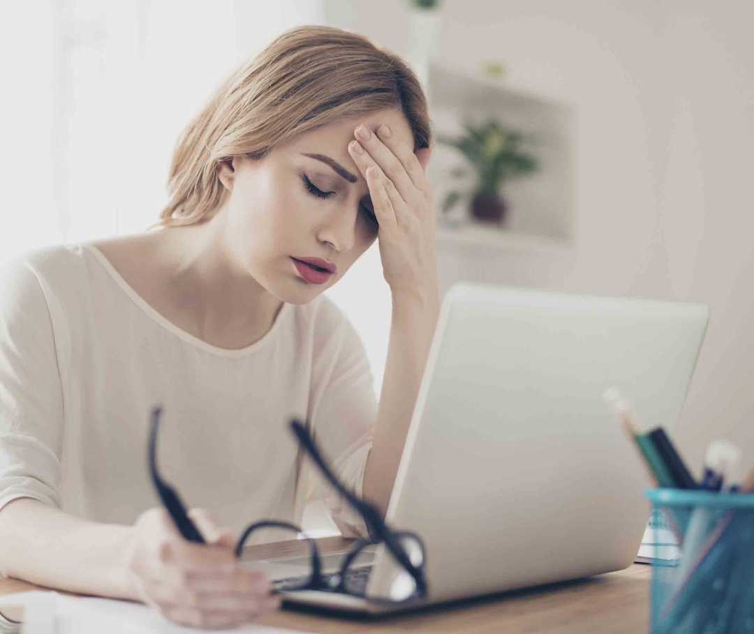 Migräne - eine schwere neurologische Erkrankung: Frau hält sich den Kopf.