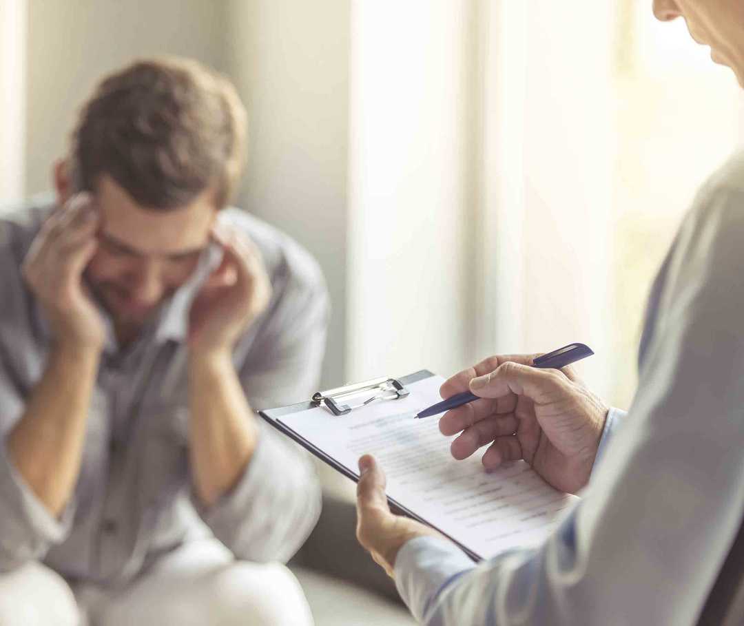 Arzt teilt einem Mann die Diagnose Migräne mit