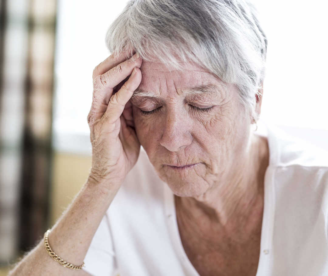 Frau mit Migräne im Alter hält sich den Kopf.