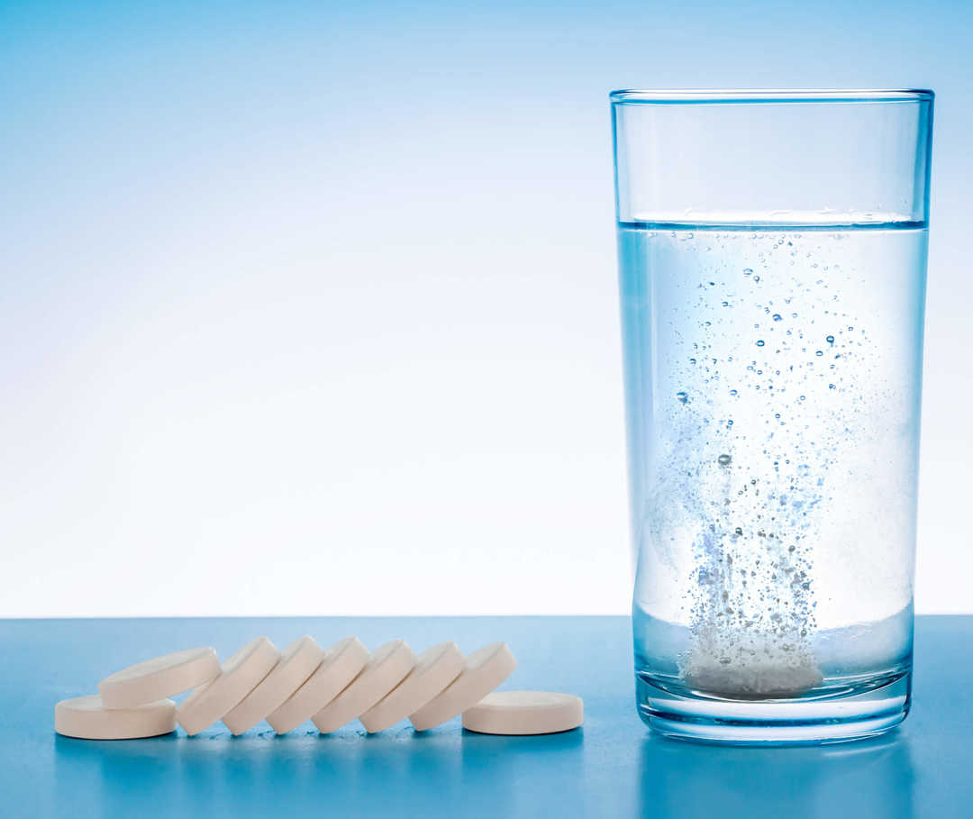 Schmerzmittel bei Migräne: Glas mit sprudelnder Brausetablette.