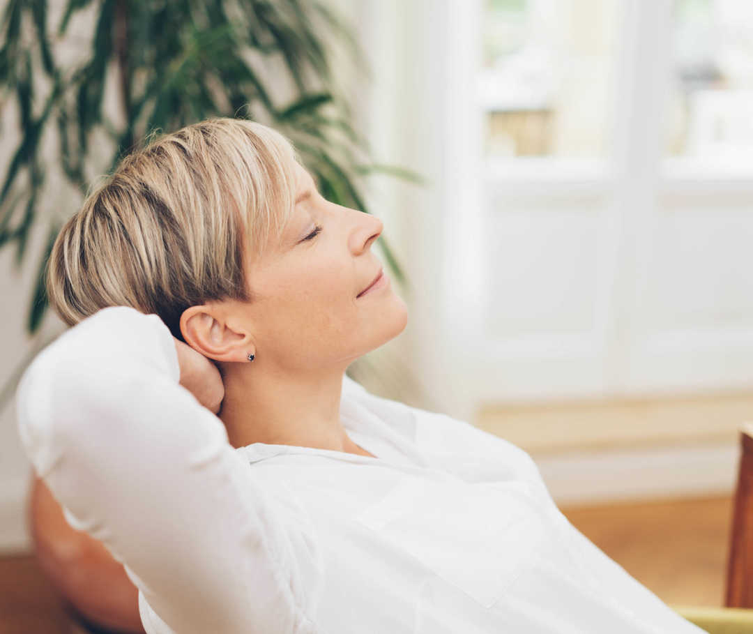 Übungen der progressiven Muskelenstapnnung nach Jacobson gegen Migräne: Frau lehnt sich entspannt zurück.