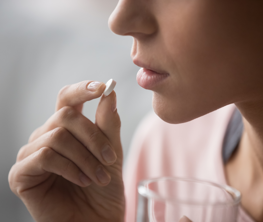 Frau nimmt Betablocker in Form einer Tablette zur Prophylaxe von Migräne ein.