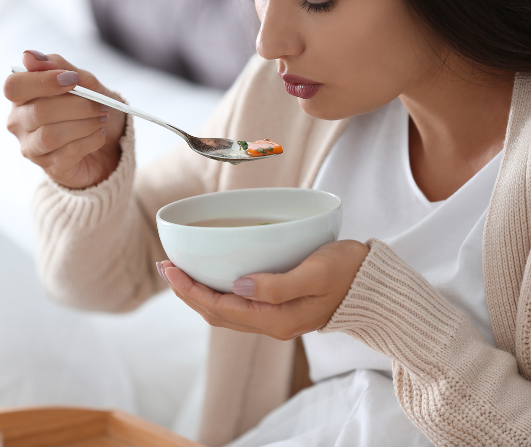 Fasten ist bei Migräne nicht verboten, aber du solltest vorher mit deinem Arzt sprechen. Eine Frau isst eine leichte Suppe.