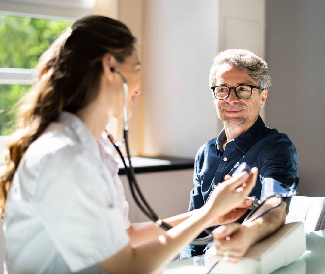 Eine Frau misst den Blutdruck bei einem Mann. 