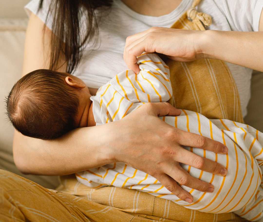 Eine Frau hält einen Säugling an ihre Brust.