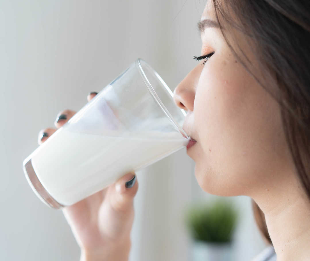 Migräne durch Milch Eine junge Frau trinkt ein Glas Milch.